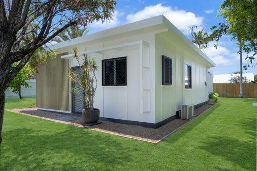 una pequeña casa blanca con un árbol en un patio en Castle View Cottage, en Townsville