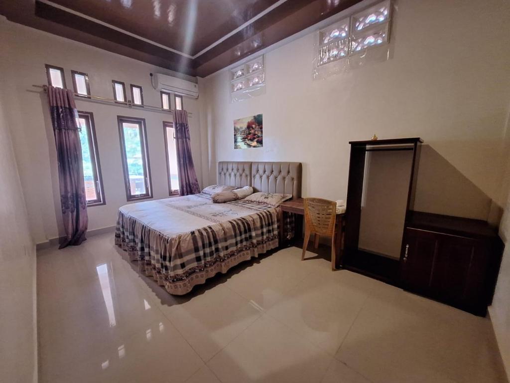 a bedroom with a bed and a table and windows at Nias Shady Palm surfcamp in Lagudri