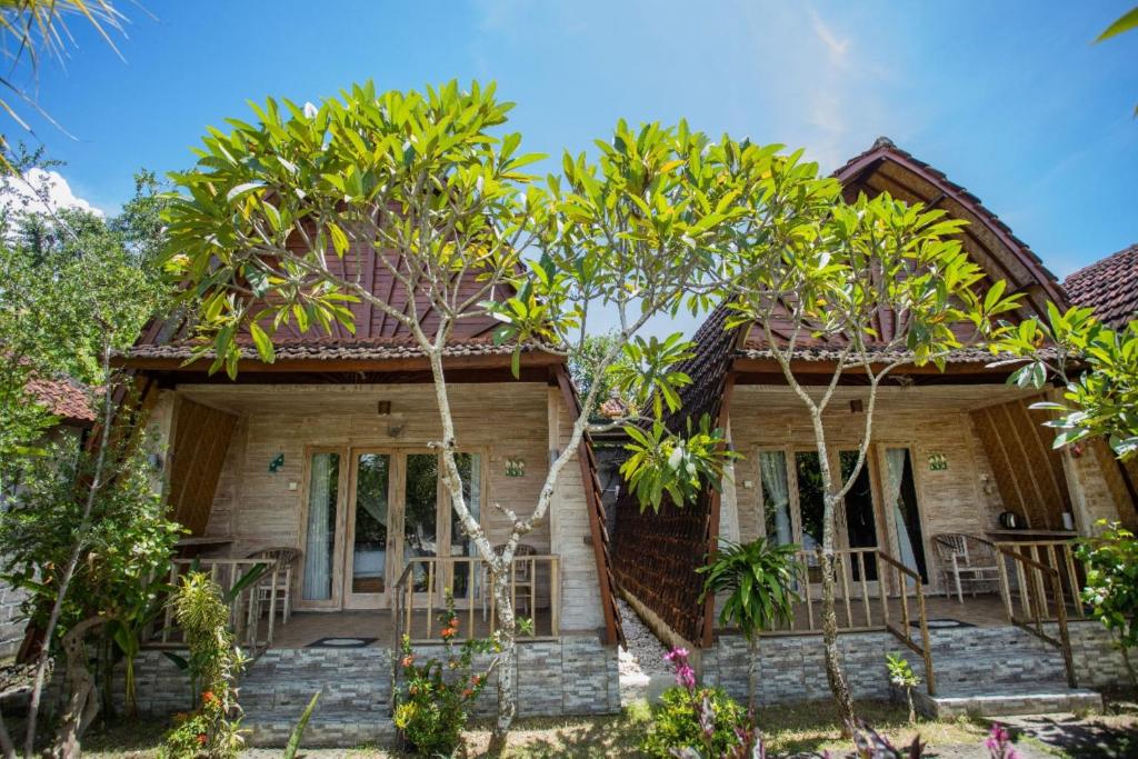 une maison en bois avec des arbres devant elle dans l'établissement Desa Sweet Cottages, à Nusa Lembongan