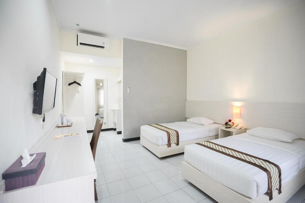 una camera d'albergo con due letti e una televisione di Cakra Kusuma Hotel a Yogyakarta