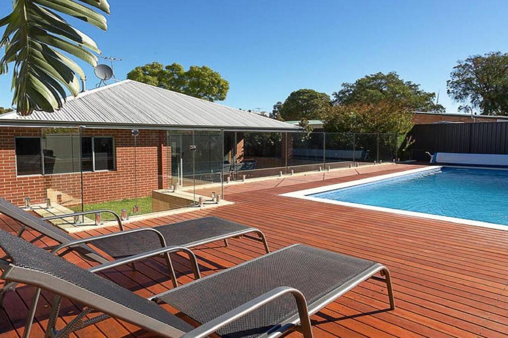 a deck with two chairs and a swimming pool at Rivervale Retreat - Spacious Family Living in Perth