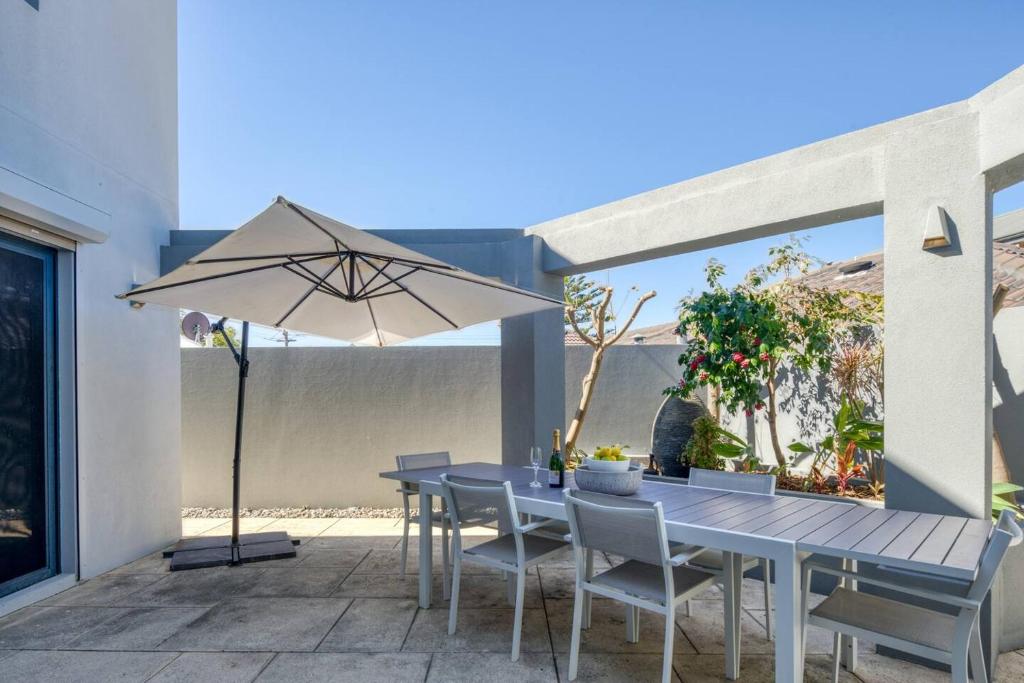 a table with chairs and an umbrella on a patio at 'Karrinyup Villa' Lush Indoor-Outdoor Living in Perth
