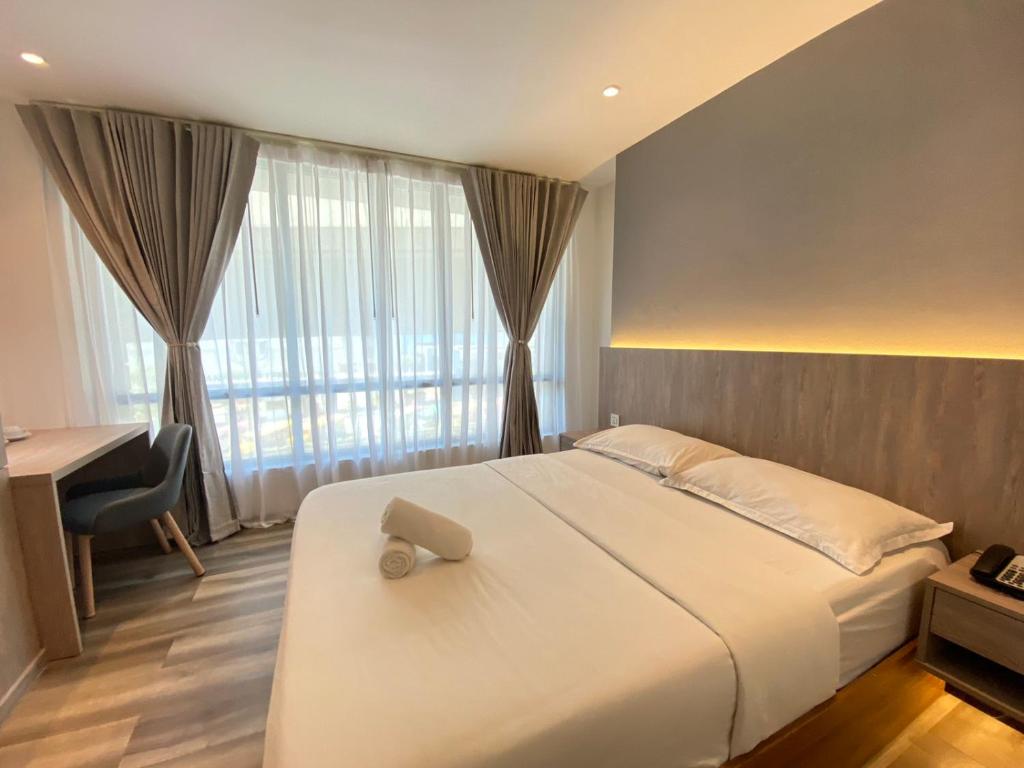 a bedroom with a bed and a desk and a window at Mc Hotel Fairview in Manila