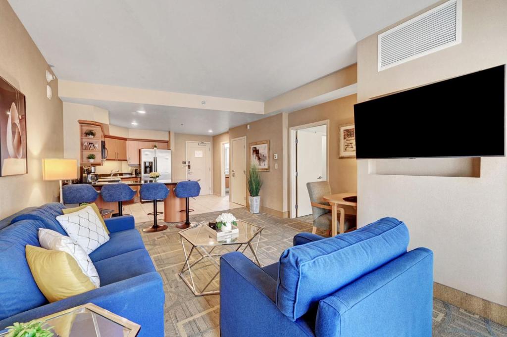sala de estar con muebles azules y TV de pantalla plana en Royal Oasis Suite at Platinum Hotel-Strip Views en Las Vegas