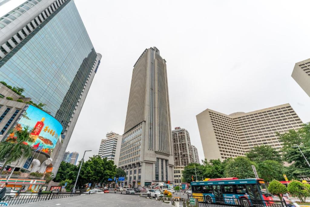 a city street with a bus in front of tall buildings at The Legend Fragrance Hotel- Free Deliver Service to Canton Fair Complex during Canton Fair Period in Guangzhou