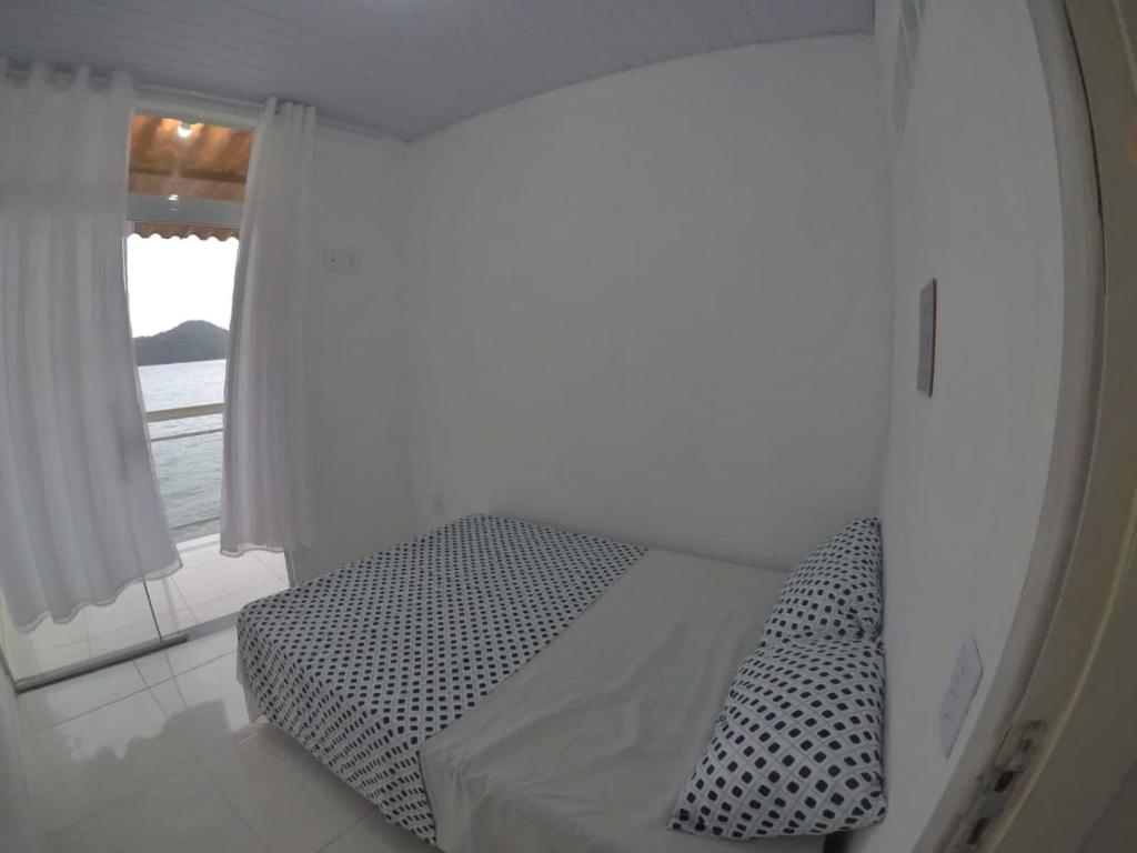 ein weißes Zimmer mit einem Bett und einem Fenster in der Unterkunft Casa no Mar de Junqueira in Mangaratiba