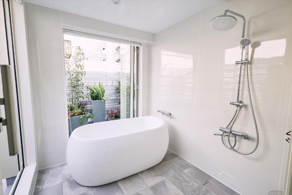 un bagno bianco con vasca e WC di 「まちのオアシス」STAY UWU 005 空を眺める半露天風呂 a Kochi