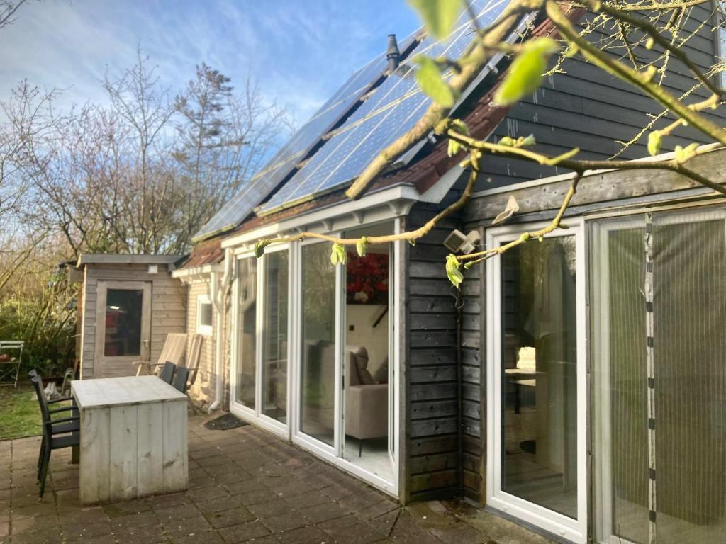 uma extensão para um conservatório com um telhado inclinado em 8-person house with fitted kitchen, sauna, and beautiful garden em Oostmahorn