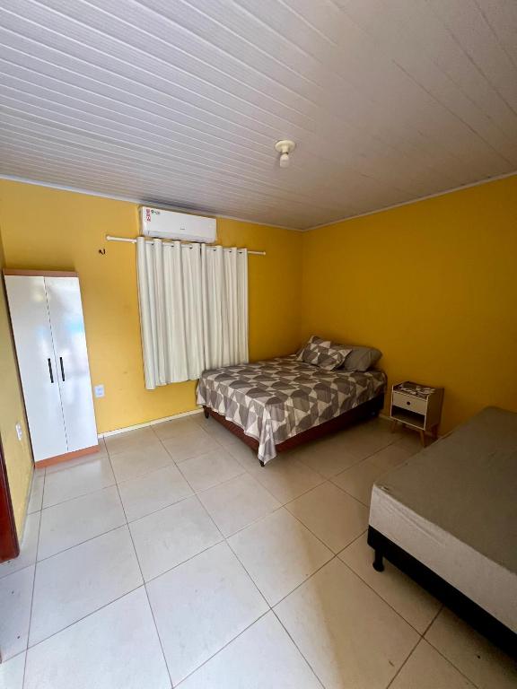 um quarto com paredes amarelas, uma cama e uma janela em Espaço Prime SLZ em São Luís