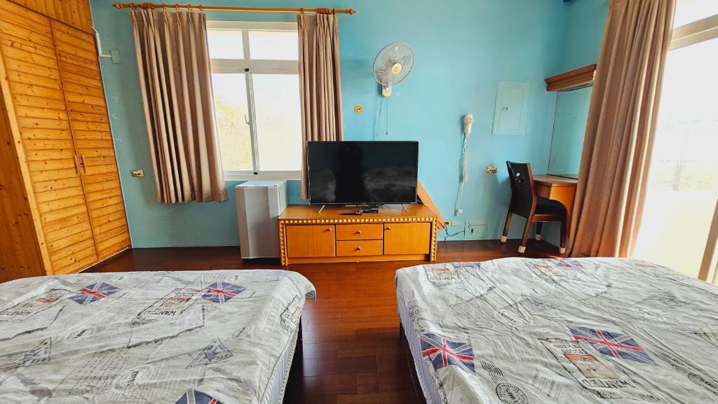 a bedroom with two beds and a flat screen tv at Sea Front Homestay in Magong