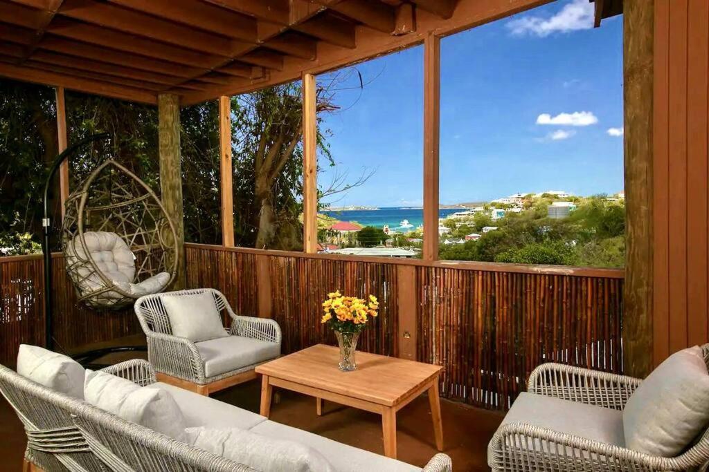 un porche con sillas y una mesa con un jarrón de flores en Sea View & Sunset Haven, en Enighed