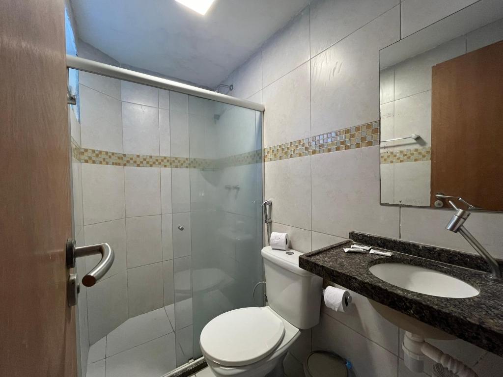 y baño con aseo, lavabo y espejo. en Pousada Unaí, en Porto de Galinhas