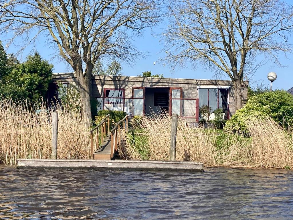 una casa sentada al lado de un cuerpo de agua en Tolles 2 Pers Haus König mit Hafenblick am Lauwersmeer, en Anjum