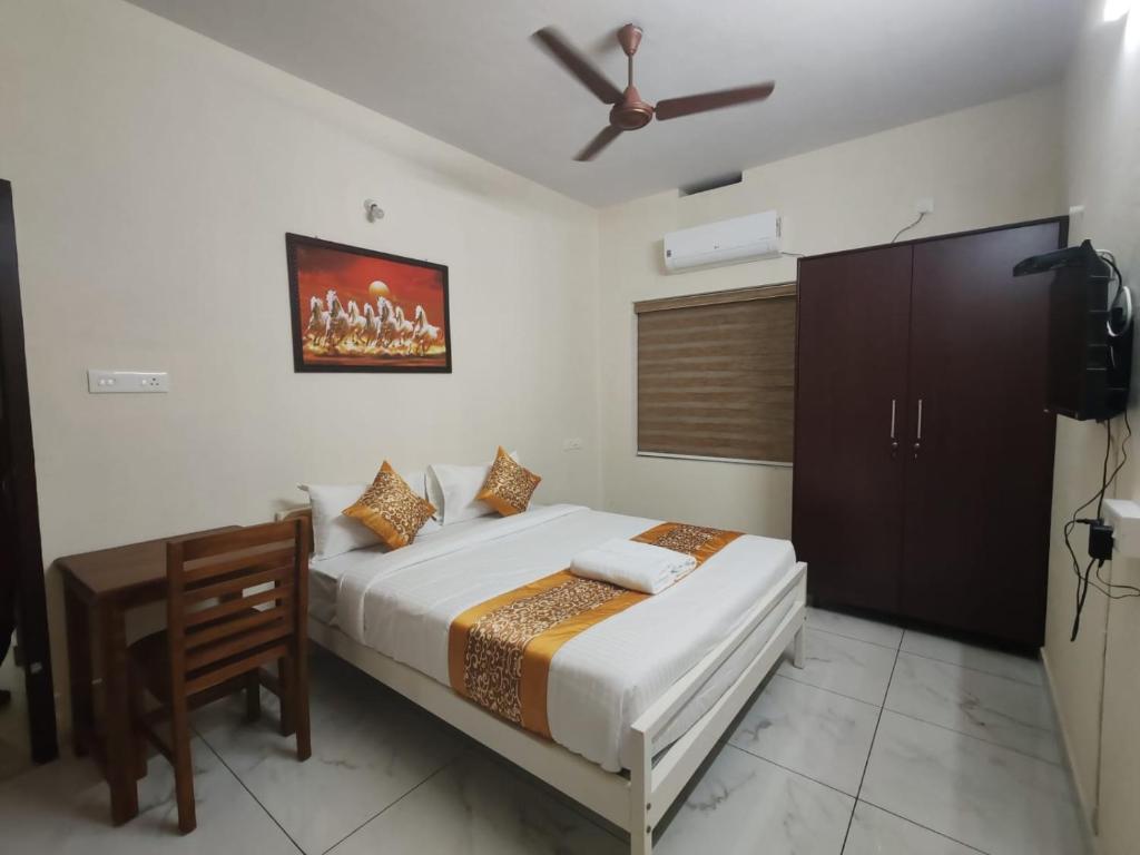 a bedroom with a bed and a table and a ceiling fan at Greenview Royal Stay Near Amrita Hospital Edappally in Cochin