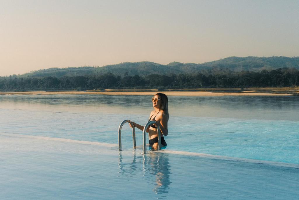 una mujer sentada en el agua en un cuerpo de agua en Chiangkhan River Mountain Resort en Chiang Khan