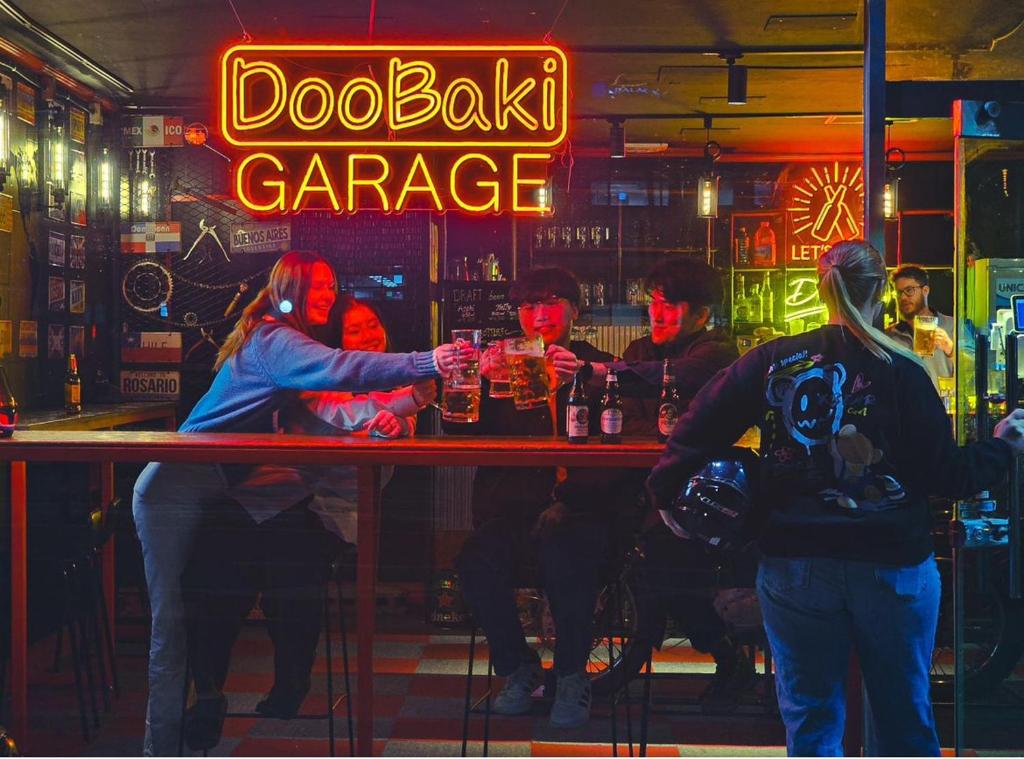 a group of people standing at a bar in a pub at Doobaki Hostel in Gyeongju