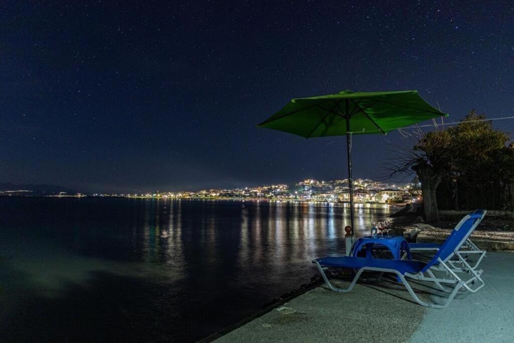 a chair and an umbrella and water at night at MAKAROUNIS THEA II in Petalidhion
