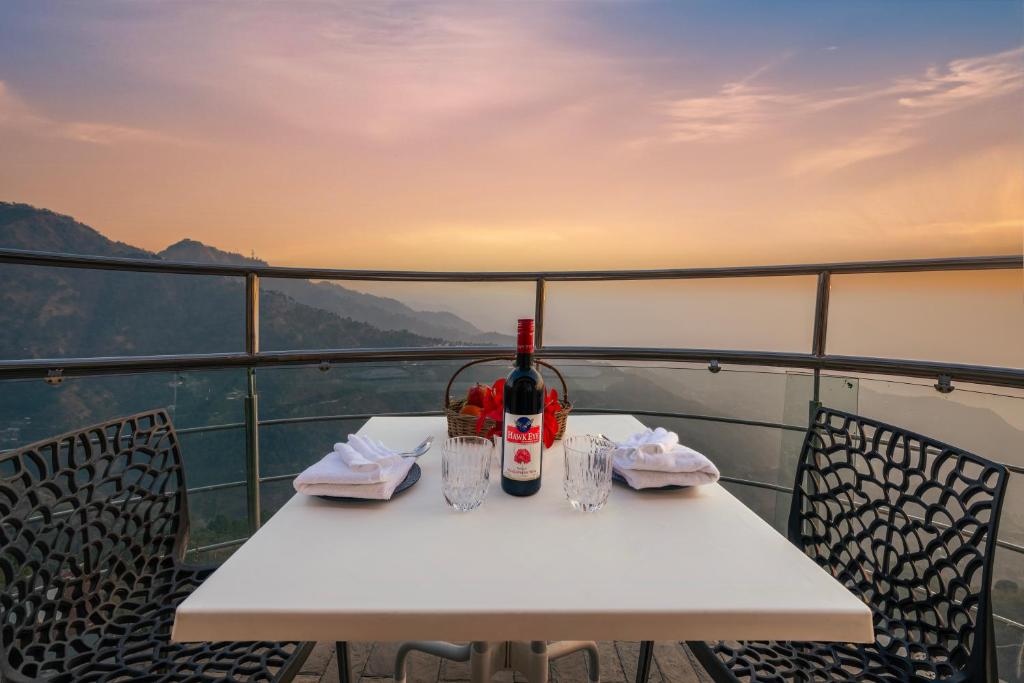 a white table with a bottle of wine on a balcony at The Trident I Kasauli by Humble stay villa in Kasauli