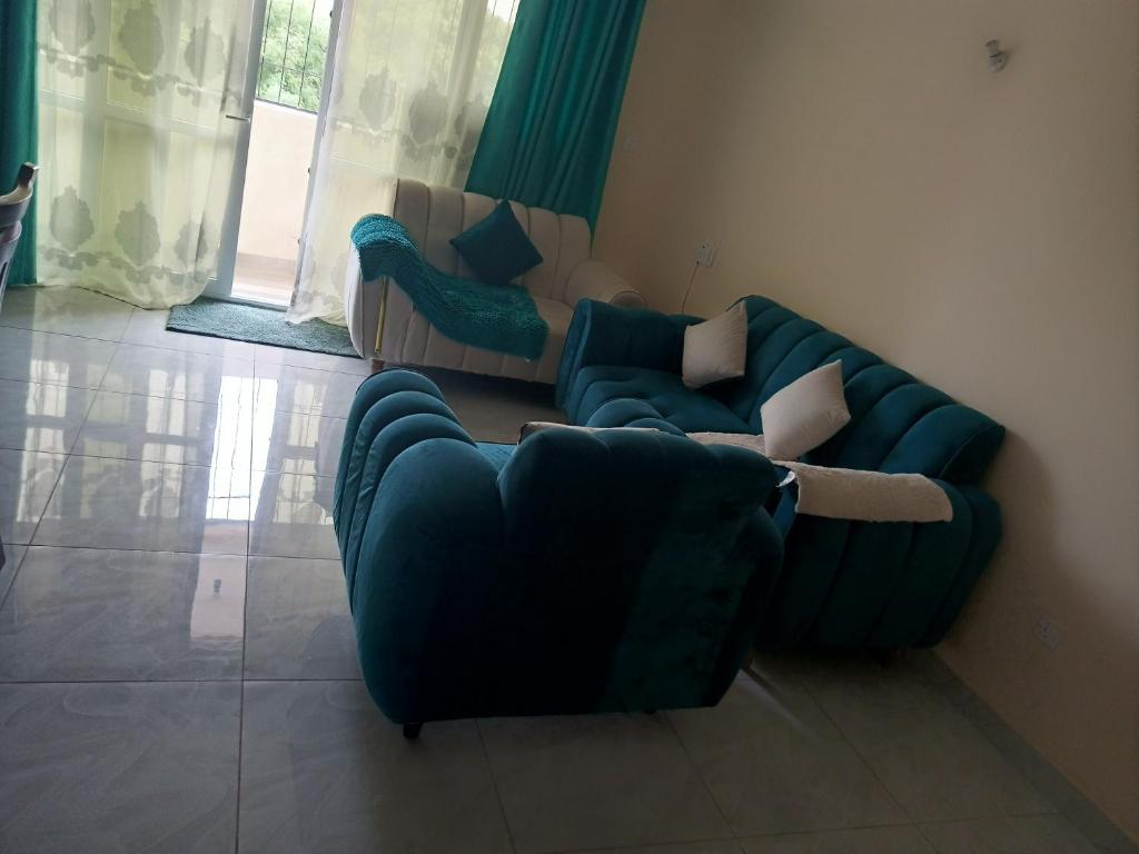 een woonkamer met een blauwe bank en 2 stoelen bij Lizzy B Classic Apartments Mtwapa in Mombasa