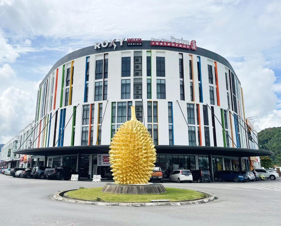 un grand bâtiment avec une grande sculpture jaune devant lui dans l'établissement Roxy Hotel Serian, à Serian
