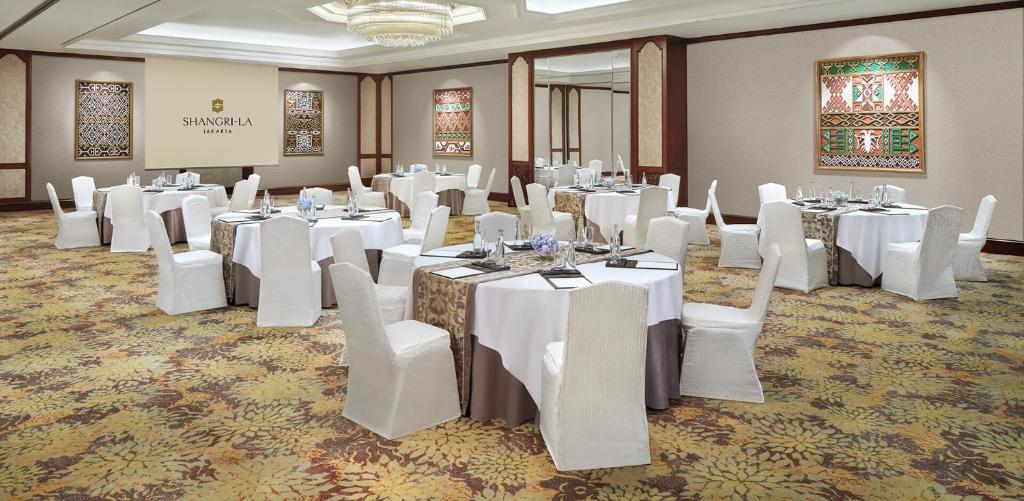 a banquet room with white tables and white chairs at Shangri-La Jakarta in Jakarta