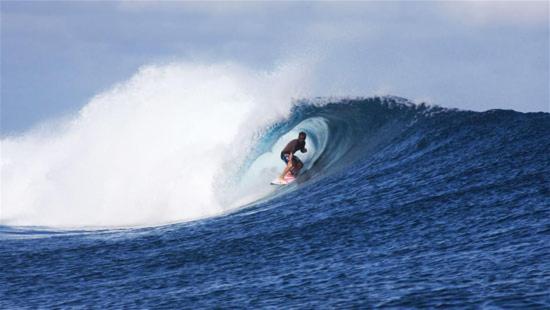 una persona che cavalca un'onda su una tavola da surf nell'oceano di FS Hotel & villa ad Arugam