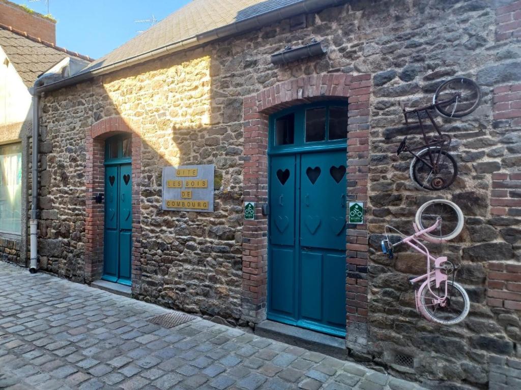 ein Backsteingebäude mit blauen Türen und einem Fahrrad darauf in der Unterkunft Les bois de combourg in Combourg