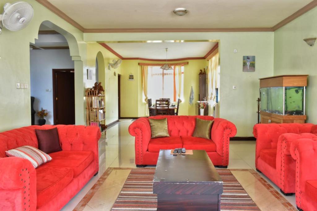 a living room with red couches and a table at tulia liqizo homestay in Mombasa