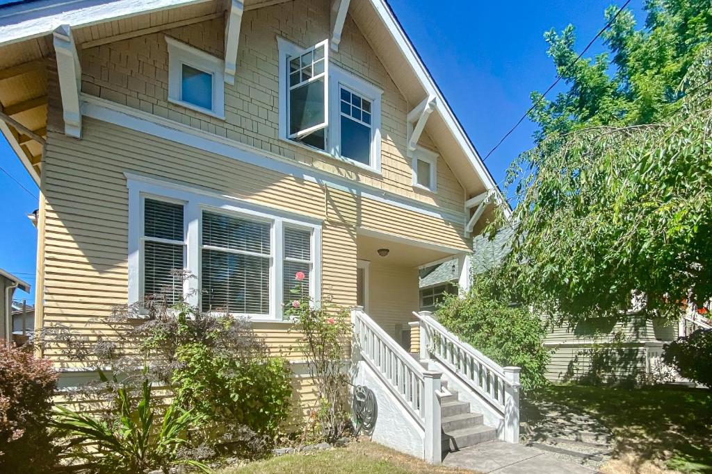 a yellow house with a white staircase in front of it at West Woodland Wonder in Seattle