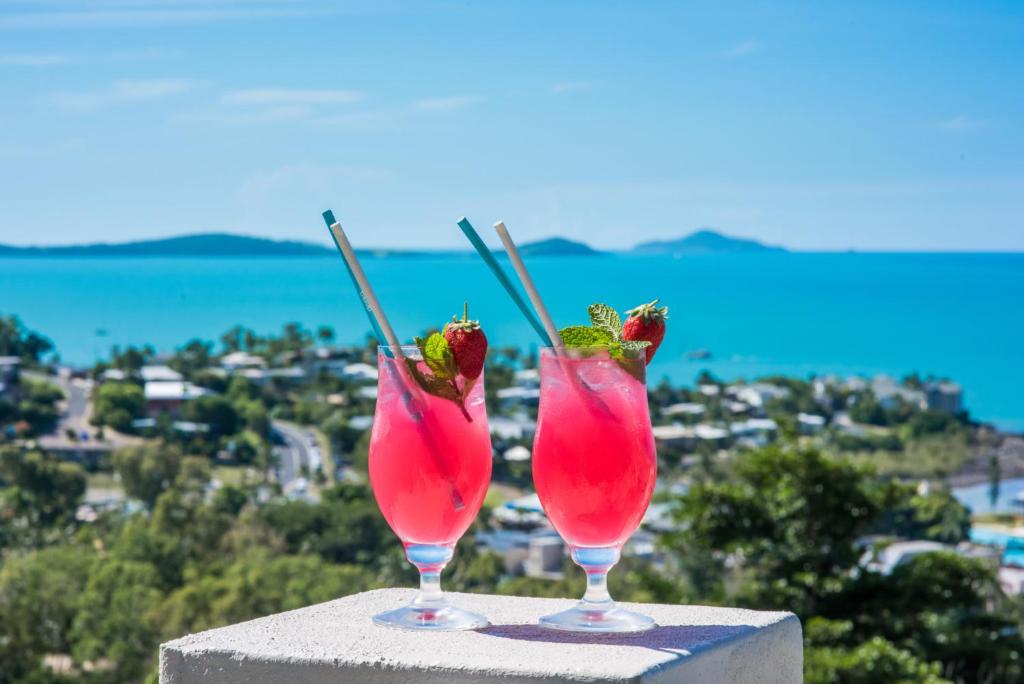 two pink cocktails sitting on top of a ledge at Oscar's View - Airlie Beach in Airlie Beach