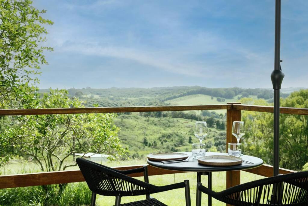 un tavolo e sedie su un balcone con vista di The Honey Barn, Wabi-Sabi Cottage Byron Hinterland a Clunes