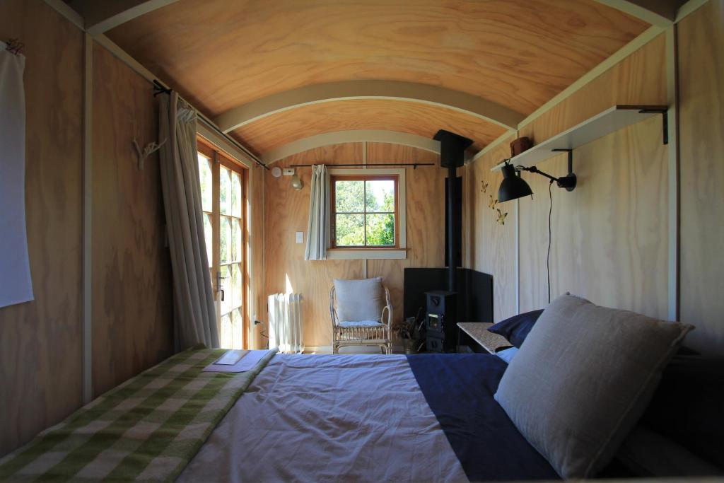 1 dormitorio con 1 cama en una habitación con ventana en The Bird Hide - rustic luxury by the water en Dunedin