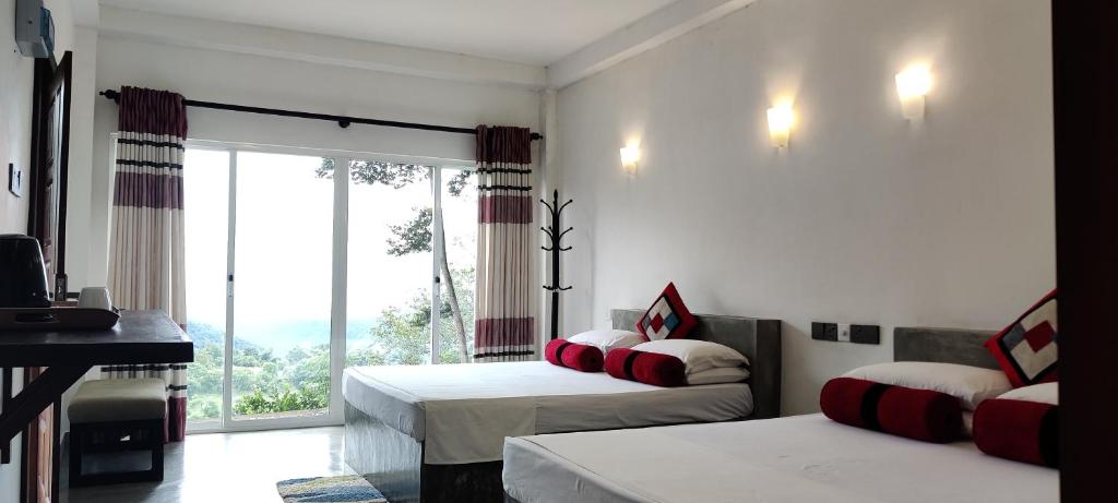 a bedroom with two beds and a large window at Sobaway Resorts in Ella