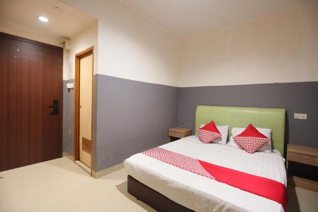 Un dormitorio con una cama con almohadas rojas. en OYO 93667 Penginapan Pelangi en Batam Centre