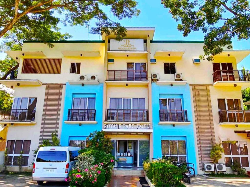 公主港的住宿－Royale Parc Hotel Puerto Princesa Palawan，一座蓝色和白色的建筑,前面有停车位