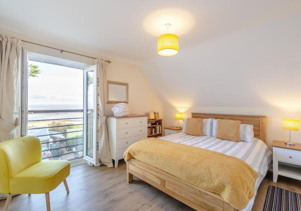 een slaapkamer met een bed, een stoel en een raam bij Pebblesea in Whitstable