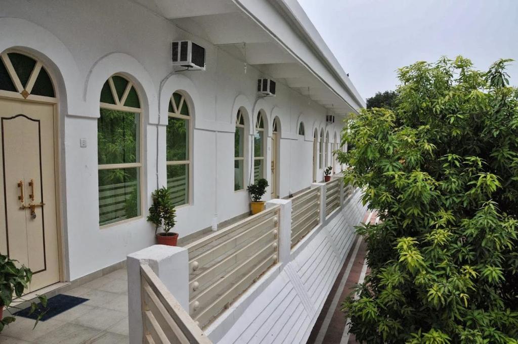 a white house with trees on the porch at Hotel Bhajgovindam in Haridwār