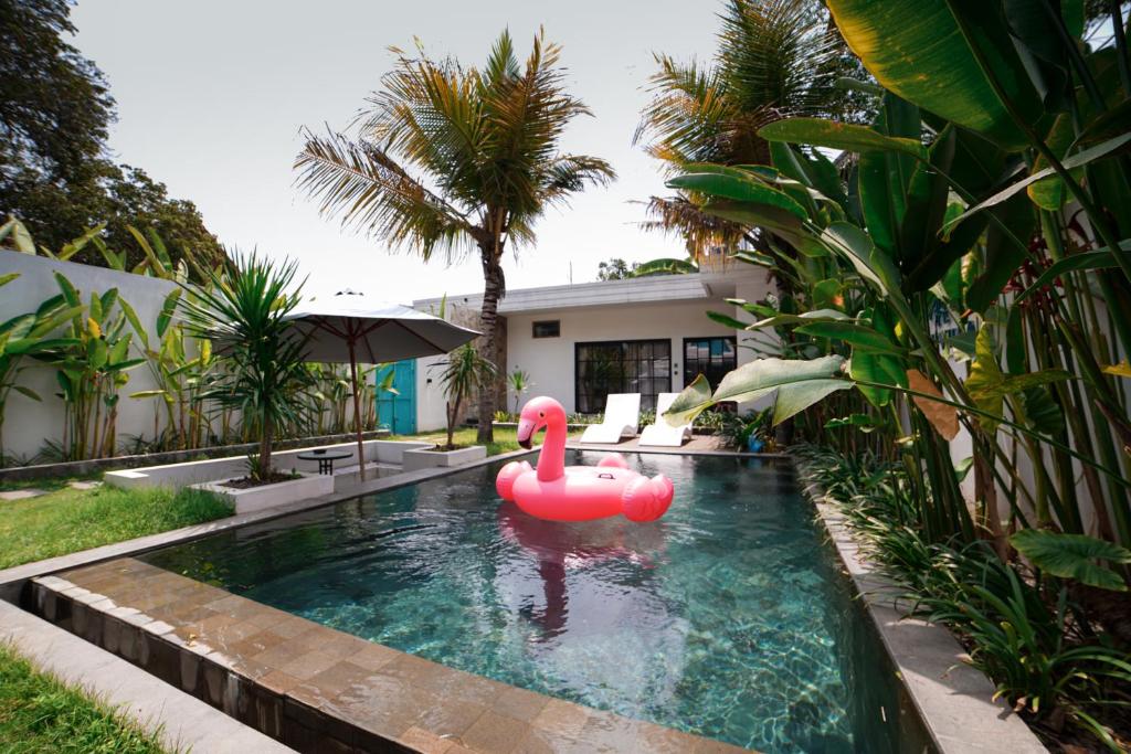 un cigno rosa in una piscina di fronte a una casa di Ubu Villa Prambanan - 3 Bedrooms Villa near Prambanan Temple a Prambanan
