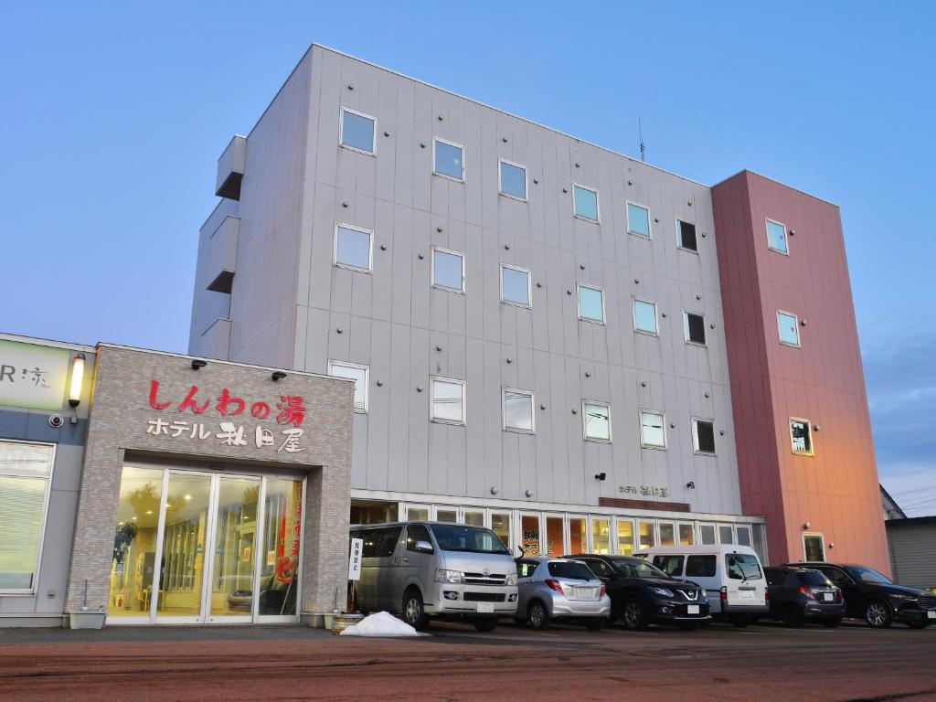 北斗HigashimaeOnsen Shinwanoyu Hotel Akitaya的一座大楼，停车场里停满了汽车