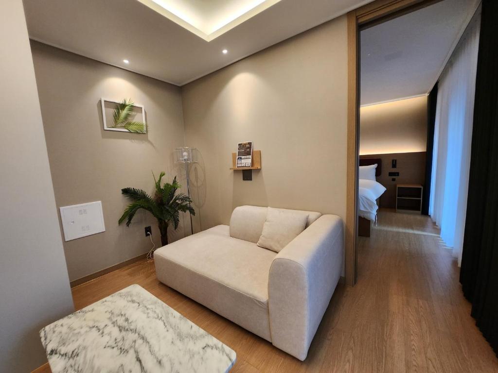 uma sala de estar com um sofá e um quarto em Soyou By Haeundae em Busan