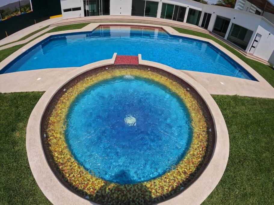 uma vista superior de uma grande piscina azul com flores à sua volta em Casa de Lujo/10 minutos Estacas/ Cancha Frontón em Ticumán
