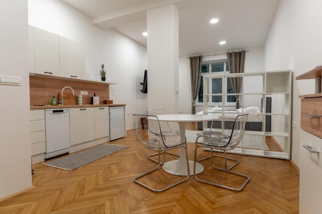 cocina con armarios blancos, mesa y sillas en Villa Sofija, en Liubliana