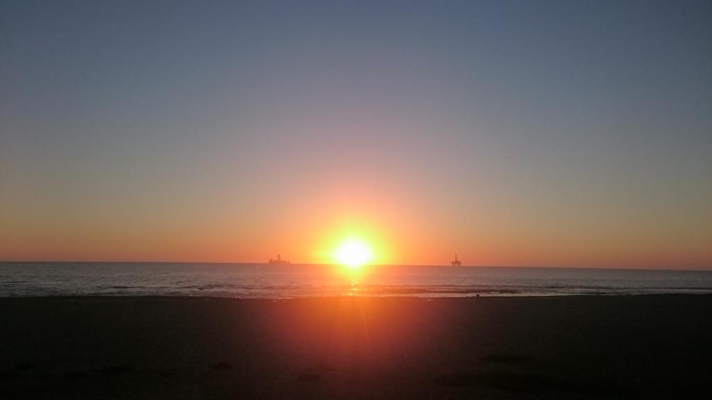 a sunset on the beach with the sun setting in the distance at Ietzie Longbeach in Swakopmund