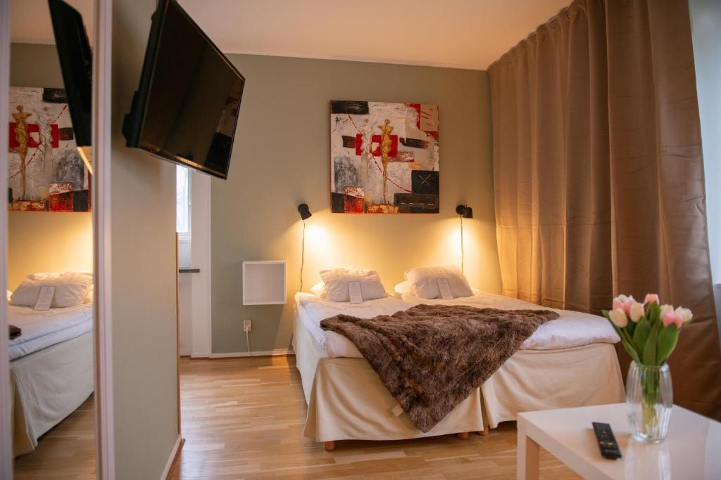 a hotel room with two beds and a flat screen tv at Slottshotellet Annex in Kalmar