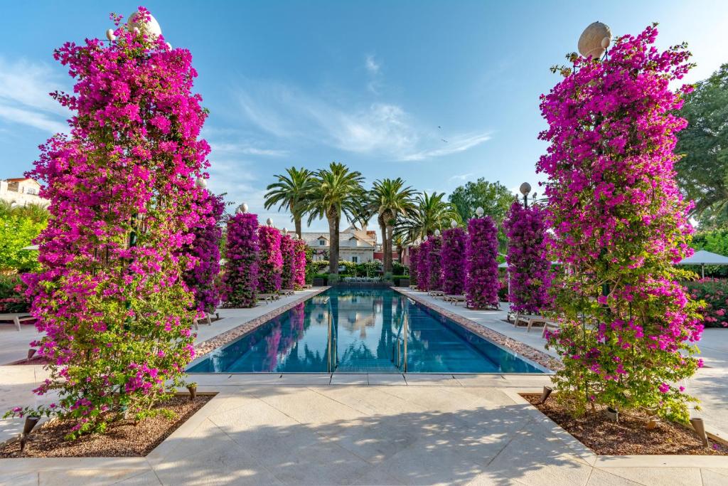 a row of purple flowers around a swimming pool at Hotel Lemongarden - Adults Only in Sutivan