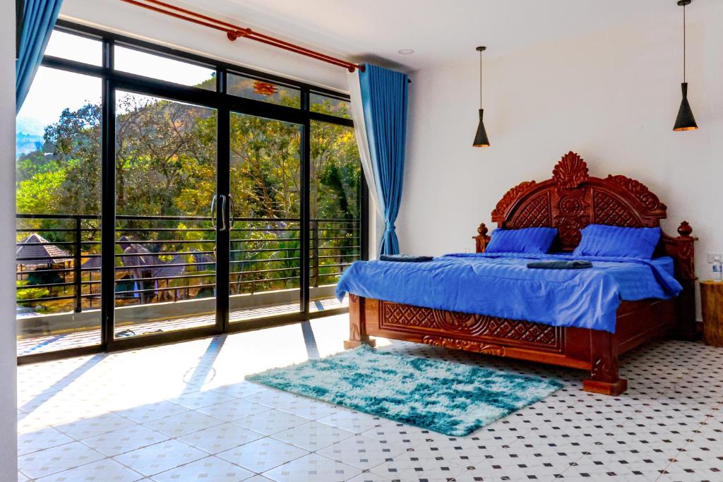 sypialnia z łóżkiem i dużym oknem w obiekcie Kampot Hill Lodge w mieście Kâmpôt