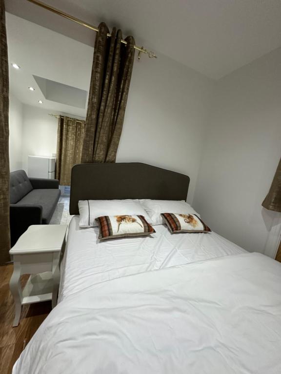 a large white bed with two pillows on it at 4TH Studio Flat a Family Luxury London Home A Fully Equipped and furnished Studio With a King Size Bed And a Futon-Sofa Bed A Baby Cot A Kitchenette With a Private Toilet and Bath a Garden For up to 4 Guests and Free Parking in Lewisham