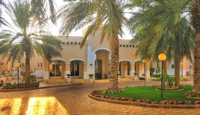 a courtyard with palm trees in front of a building at Vivienda Hotel Villas in Riyadh