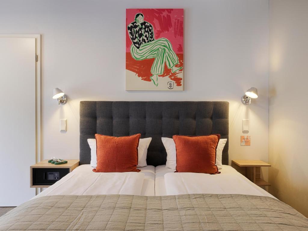 a bedroom with a large bed with orange pillows at Zur Stadt Mainz - by homekeepers in Würzburg