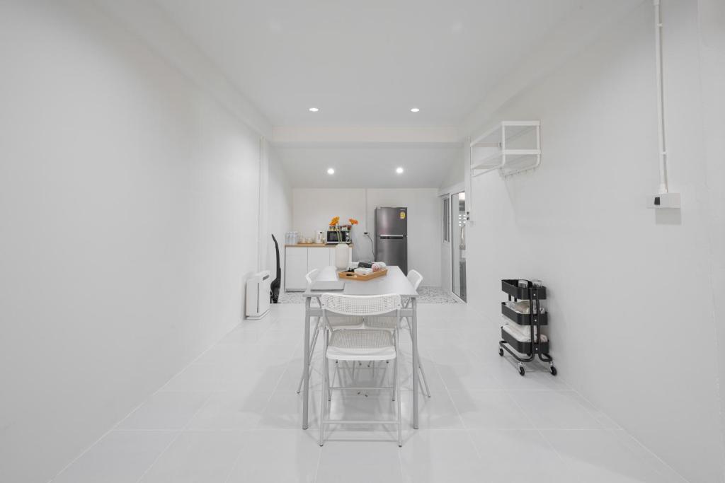 a white kitchen with a table and a refrigerator at Cozy home near city and air port in Chiang Mai